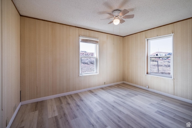 unfurnished room featuring a wealth of natural light, a textured ceiling, and wood finished floors
