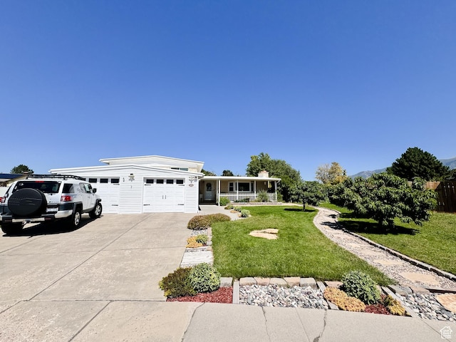 view of front of house featuring an attached garage, covered porch, concrete driveway, and a front lawn