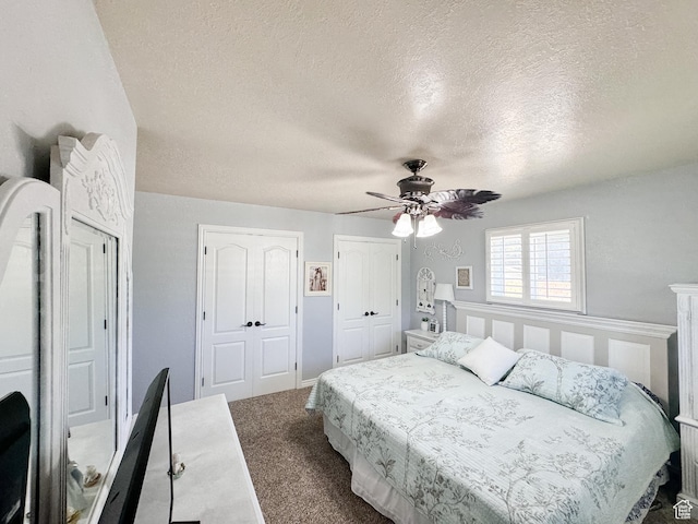 carpeted bedroom with two closets, ceiling fan, and a textured ceiling