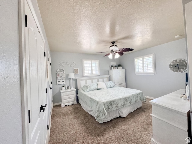 bedroom with multiple windows, carpet floors, a textured ceiling, and baseboards
