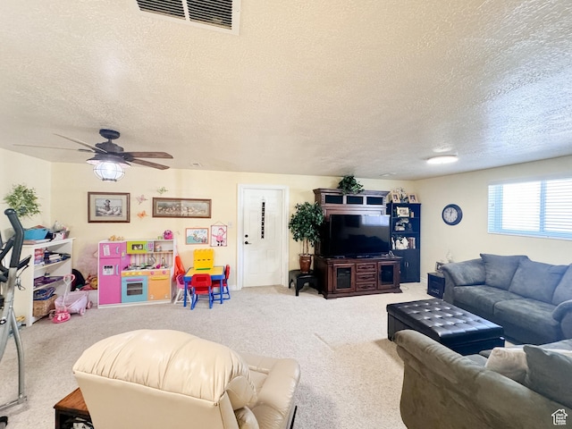 living area featuring visible vents, carpet flooring, a textured ceiling, and a ceiling fan