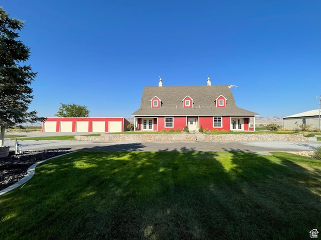 view of front facade featuring a chimney, a detached garage, a front lawn, roof with shingles, and an outdoor structure