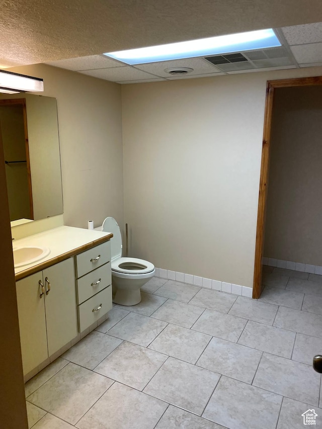 half bath featuring baseboards, toilet, a paneled ceiling, and vanity