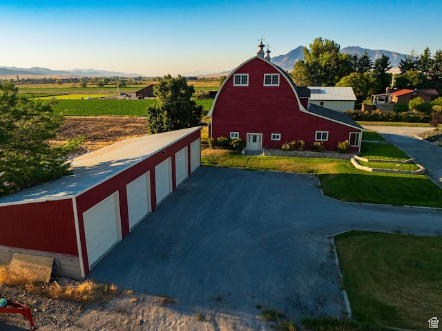 view of home's exterior with a gambrel roof, an outbuilding, a barn, a mountain view, and a garage