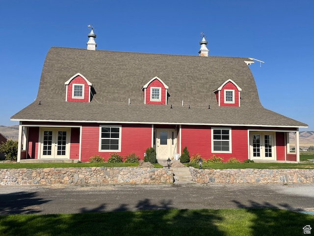 new england style home featuring a shingled roof and french doors