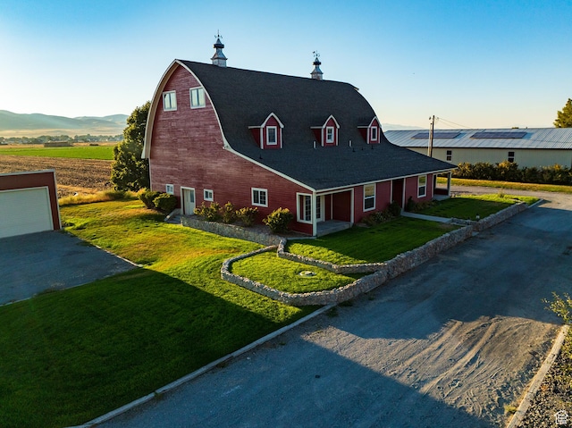 view of front of home featuring a detached garage, a front lawn, a gambrel roof, a barn, and an outbuilding