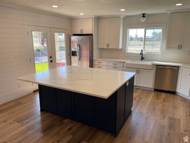 kitchen featuring a sink, light stone countertops, stainless steel appliances, white cabinets, and light wood-style floors