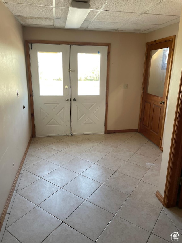 interior space featuring baseboards, light tile patterned floors, and a drop ceiling