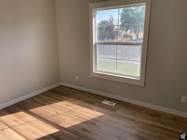 empty room featuring baseboards, visible vents, and wood finished floors