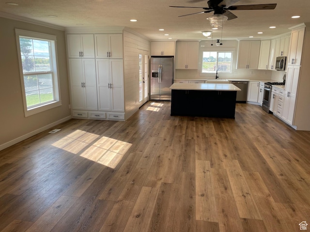 kitchen featuring light countertops, wood finished floors, a center island, stainless steel appliances, and ceiling fan