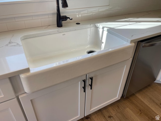 room details featuring white cabinetry, light stone counters, wood finished floors, and dishwasher