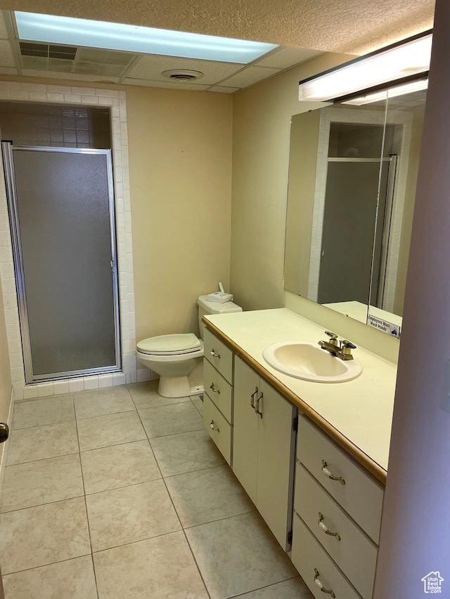 bathroom with tile patterned flooring, vanity, toilet, a shower stall, and a paneled ceiling