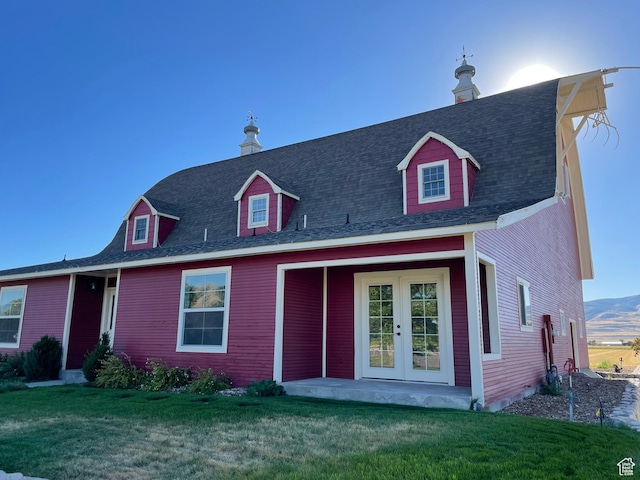 view of front facade with a front lawn, a shingled roof, and french doors