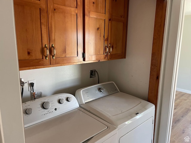 washroom with light wood finished floors, cabinet space, and separate washer and dryer