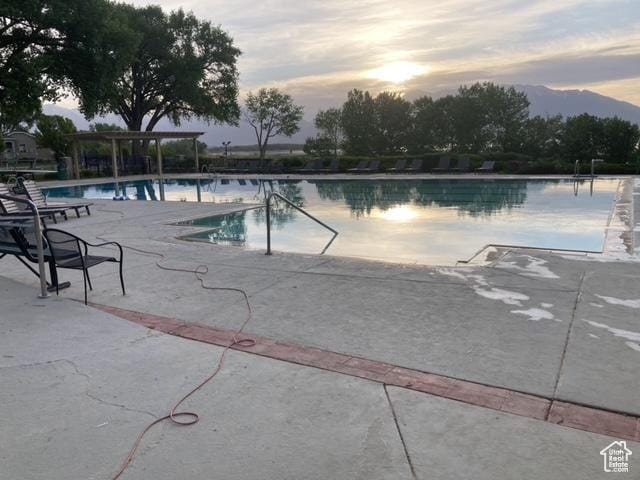 2118 S Centennial Blvd S, Saratoga Springs, UT 84045 - pool at dusk featuring a community pool, a mountain view, a patio area, and a pergola
