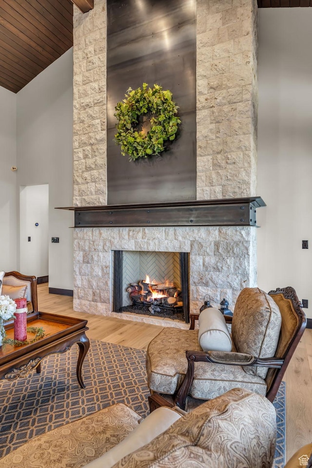 living area with wood finished floors, wooden ceiling, baseboards, a fireplace, and high vaulted ceiling