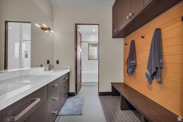 mudroom with baseboards, dark tile patterned flooring, and a sink