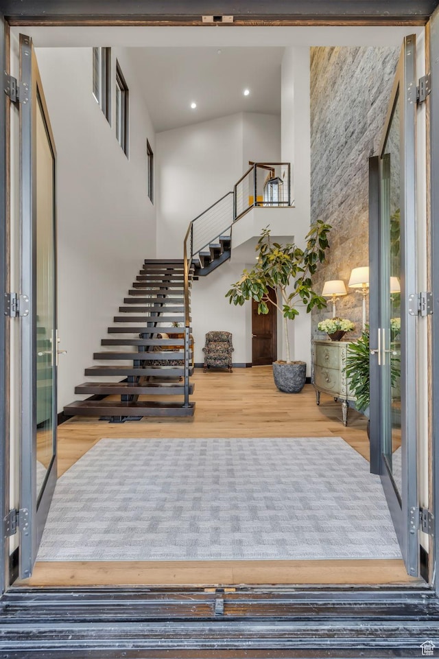 staircase featuring french doors, wood finished floors, a high ceiling, and recessed lighting