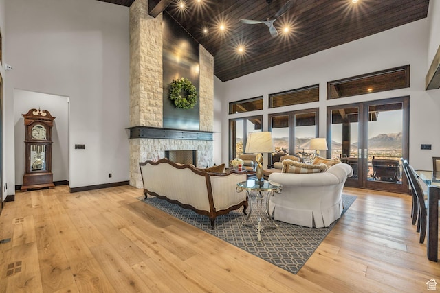living room featuring high vaulted ceiling, wood-type flooring, a ceiling fan, and a stone fireplace