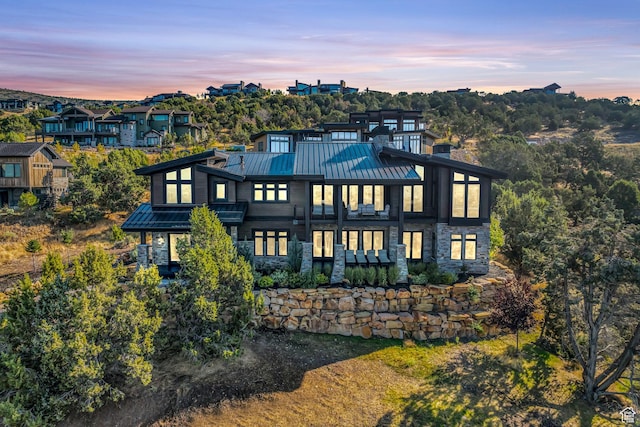 exterior space featuring a chimney, a standing seam roof, stone siding, and metal roof