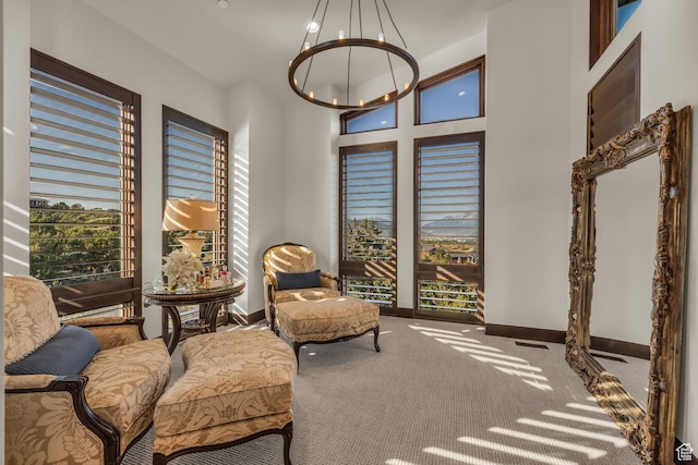 sitting room with a chandelier, carpet, and baseboards
