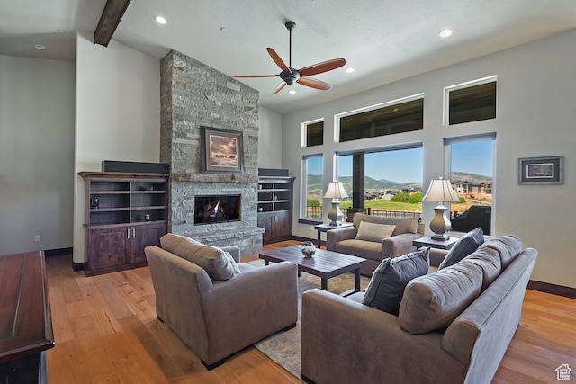 1375 E Lasso Trl, Hideout, UT 84036 - living room featuring light hardwood / wood-style flooring, beam ceiling, ceiling fan, and a stone fireplace
