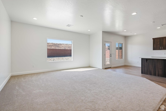 unfurnished living room featuring baseboards, a healthy amount of sunlight, visible vents, and recessed lighting
