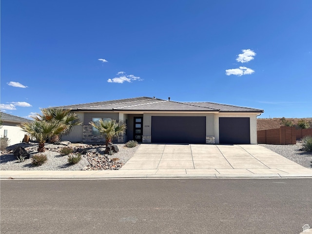 view of front of home with fence, stucco siding, an attached garage, concrete driveway, and stone siding