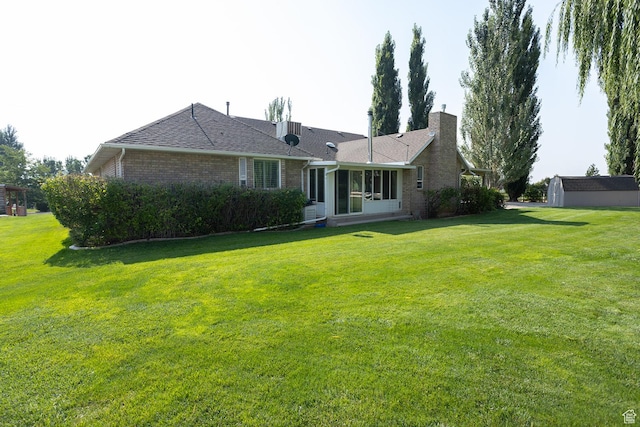 rear view of property featuring a lawn, brick siding, a chimney, and a sunroom