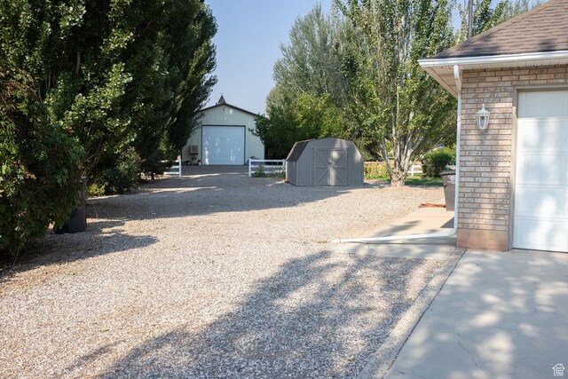 view of yard with a garage, a storage shed, and an outbuilding