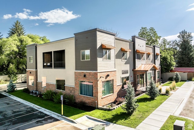 67 E 500 S Unit B102, Heber City, UT 84032 - view of home's exterior with uncovered parking, stucco siding, a yard, and brick siding