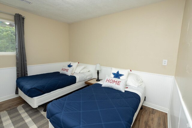 566 S Main St, Lyman, UT 84749 - bedroom with a wainscoted wall, wood finished floors, and a textured ceiling