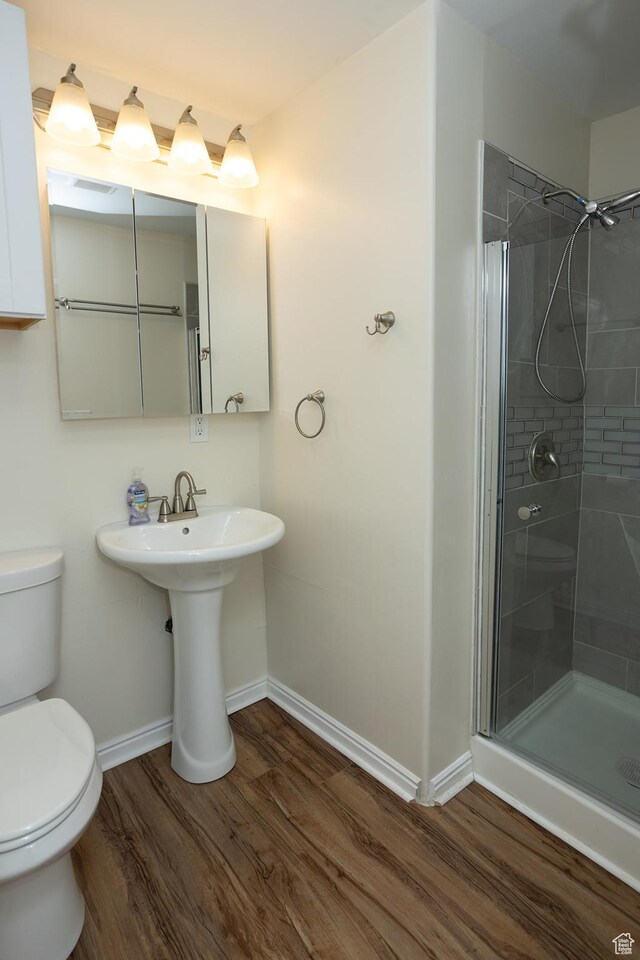 566 S Main St, Lyman, UT 84749 - bathroom with wood finished floors, toilet, baseboards, a stall shower, and a sink