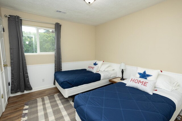 566 S Main St, Lyman, UT 84749 - bedroom featuring a wainscoted wall, wood finished floors, and a textured ceiling
