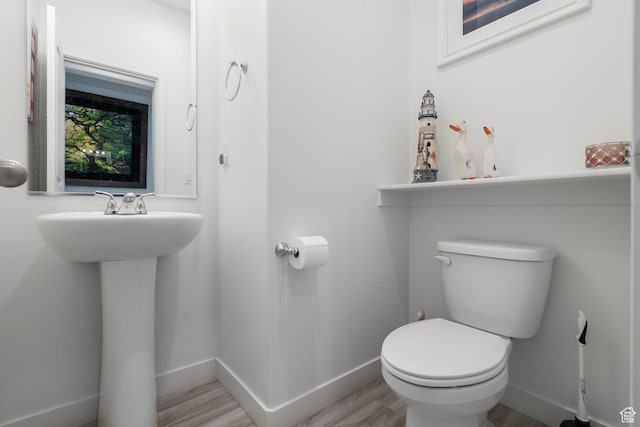 bathroom with wood finished floors, toilet, baseboards, and a sink