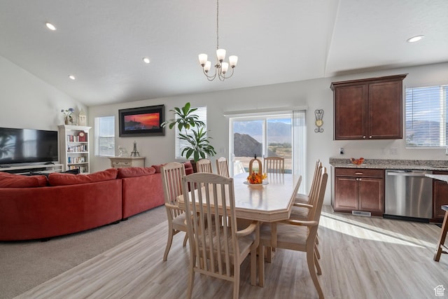 dining area with lofted ceiling, a notable chandelier, light wood finished floors, and a wealth of natural light