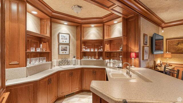 5210 Skyline Pkwy, Ogden, UT 84403 - kitchen with crown molding, light countertops, a sink, a peninsula, and brown cabinetry