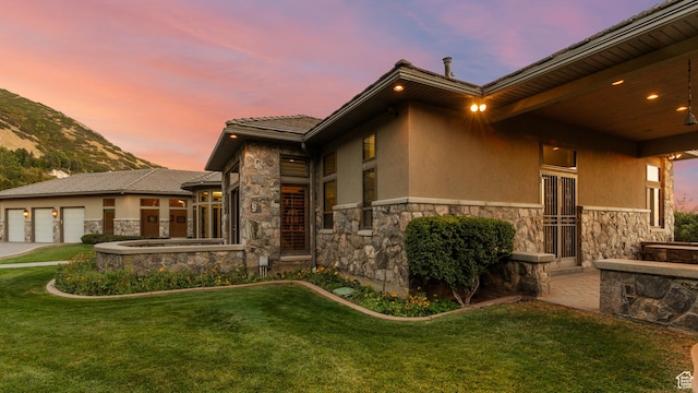 5210 Skyline Pkwy, Ogden, UT 84403 - property exterior at dusk featuring stone siding, a garage, stucco siding, and a yard