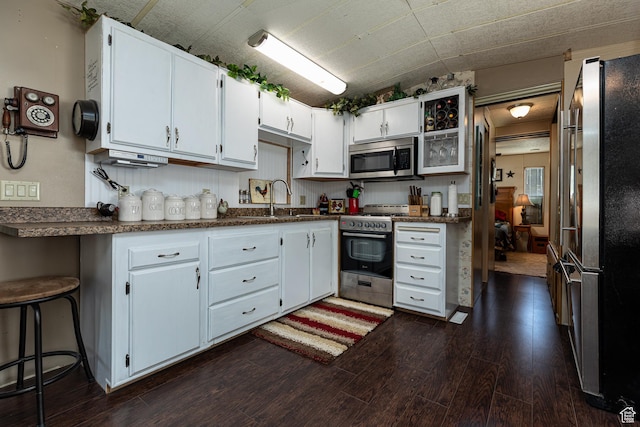 325 S Main St, Glendale, UT 84729 - kitchen featuring appliances with stainless steel finishes, dark wood-style flooring, white cabinets, and dark countertops