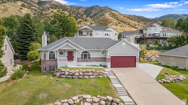 view of front of property featuring a garage, brick siding, a front lawn, driveway, and a mountain view