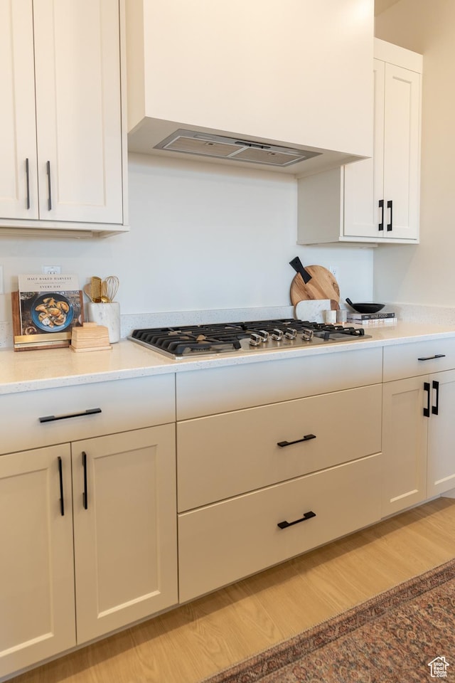5394 S Aquamarine Ln, St George, UT 84790 - kitchen featuring white cabinets, light hardwood / wood-style flooring, stainless steel gas stovetop, and wall chimney range hood