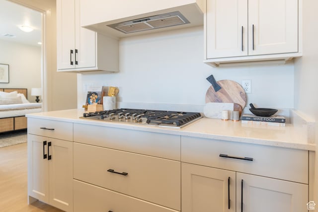 5394 S Aquamarine Ln, St George, UT 84790 - kitchen featuring light stone countertops, light wood-type flooring, ventilation hood, white cabinets, and stainless steel gas stovetop