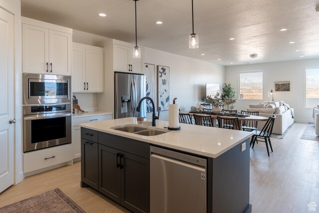 5394 S Aquamarine Ln, St George, UT 84790 - kitchen with pendant lighting, a center island with sink, sink, white cabinetry, and stainless steel appliances