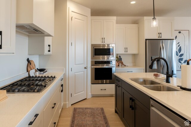 5394 S Aquamarine Ln, St George, UT 84790 - kitchen with white cabinets, wall chimney range hood, sink, hanging light fixtures, and appliances with stainless steel finishes