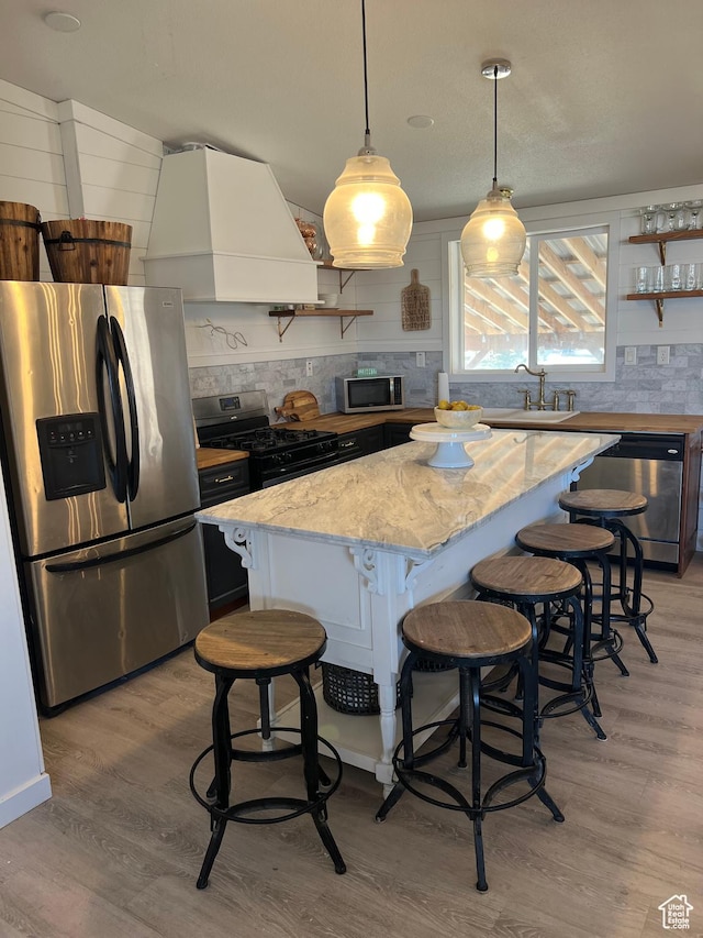 594 S Aspen Dr Unit 48, Garden City, UT 84028 - kitchen featuring light wood finished floors, a kitchen island, premium range hood, appliances with stainless steel finishes, and open shelves