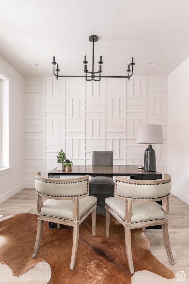 sitting room featuring a textured ceiling, baseboards, light wood-style floors, and an inviting chandelier