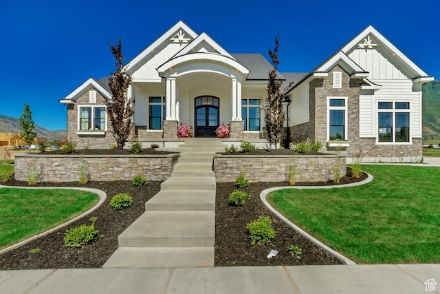 craftsman-style house featuring a front lawn, a porch, stone siding, and board and batten siding