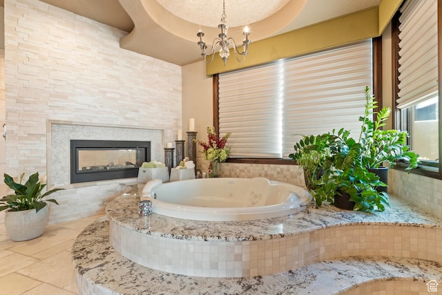 2596 E Flint St, St George, UT 84790 - bathroom featuring a tile fireplace, a chandelier, a whirlpool tub, and tile patterned flooring