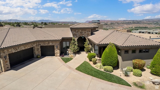 2596 E Flint St, St George, UT 84790 - mediterranean / spanish house with stucco siding, a tile roof, driveway, stone siding, and an attached garage