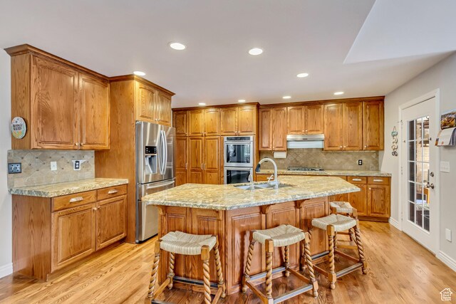 2768 W Country Classic Dr, Bluffdale, UT 84065 - kitchen featuring stainless steel appliances, under cabinet range hood, light wood-type flooring, and brown cabinetry